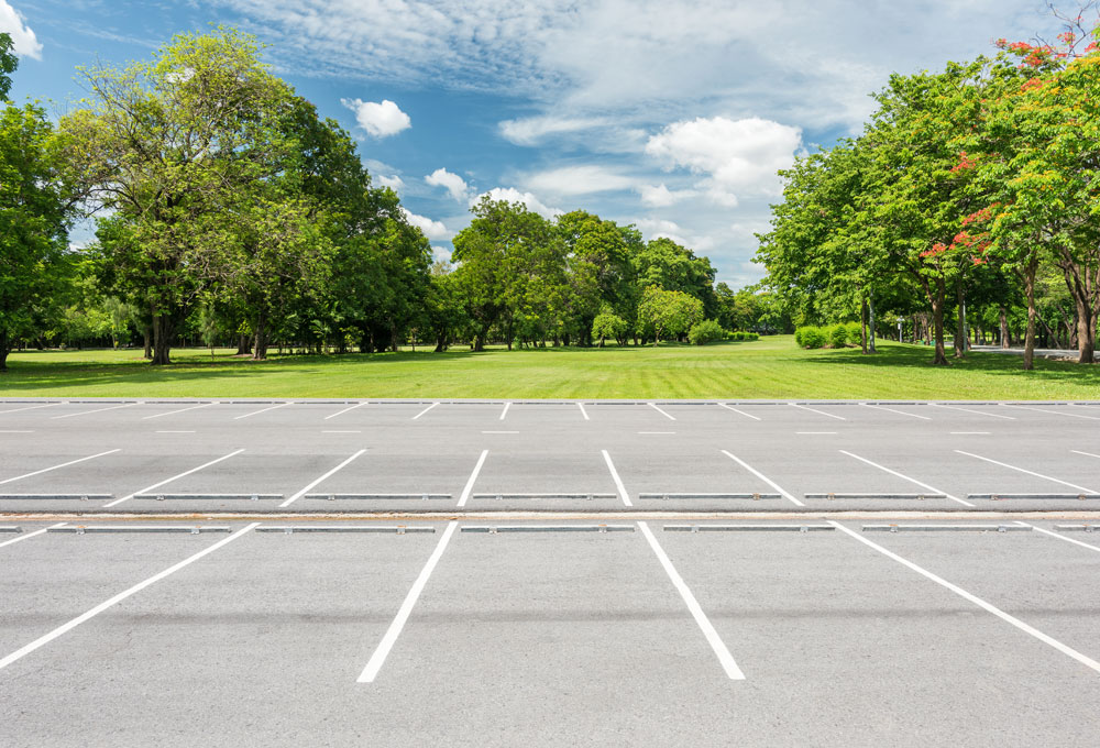 Empty parking lot surrounded by trees and grass.